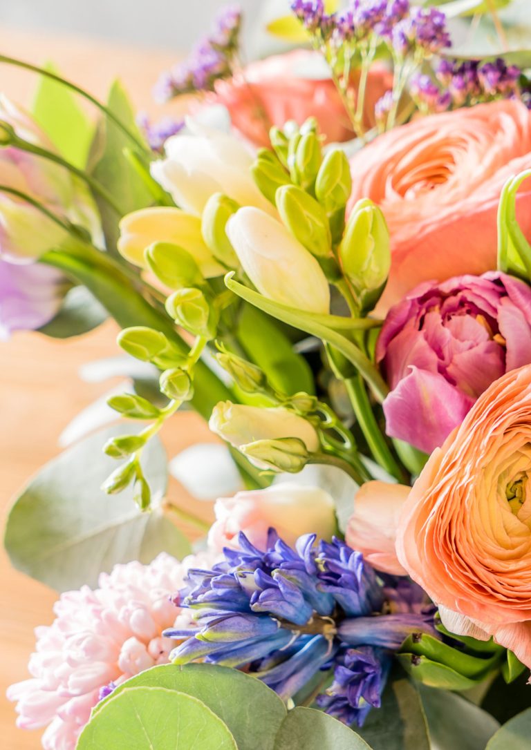 Close up photograph of a bouquet of spring flowers including peonies, bluebells, freesias, stocks.