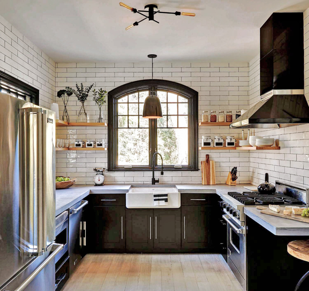 An image of a classic vintage style kitchen with modern twists. Dark cupboards contrast beautifully the fully tiled white subway tiled walls and white work surfaces. Sleek stainless steel appliances create the ultra modern juxtaposition between the old and new.