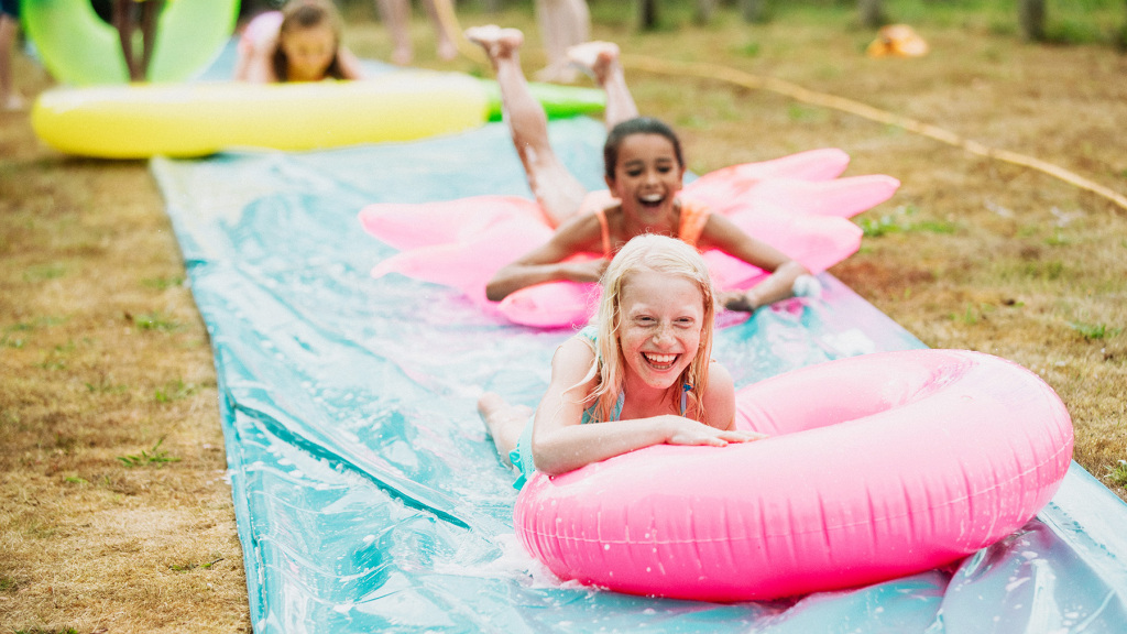 Image of children playing on a slip and slide type  back garden water toy.