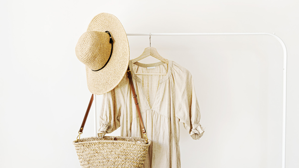 Image of a straw hat, straw shoulder bag and natural coloured linen dress.
