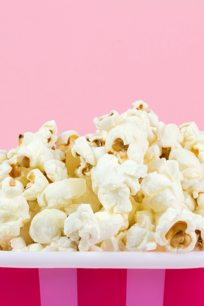 A close-up image of popcorn in a pink striped container.