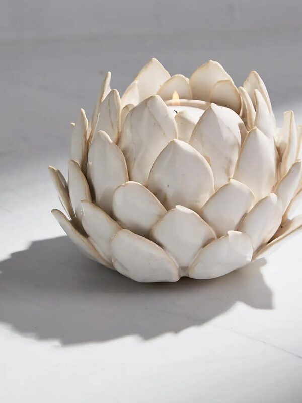 Ivory ceramic artichoke tea light holder with layered petal design and soft glaze on a light surface